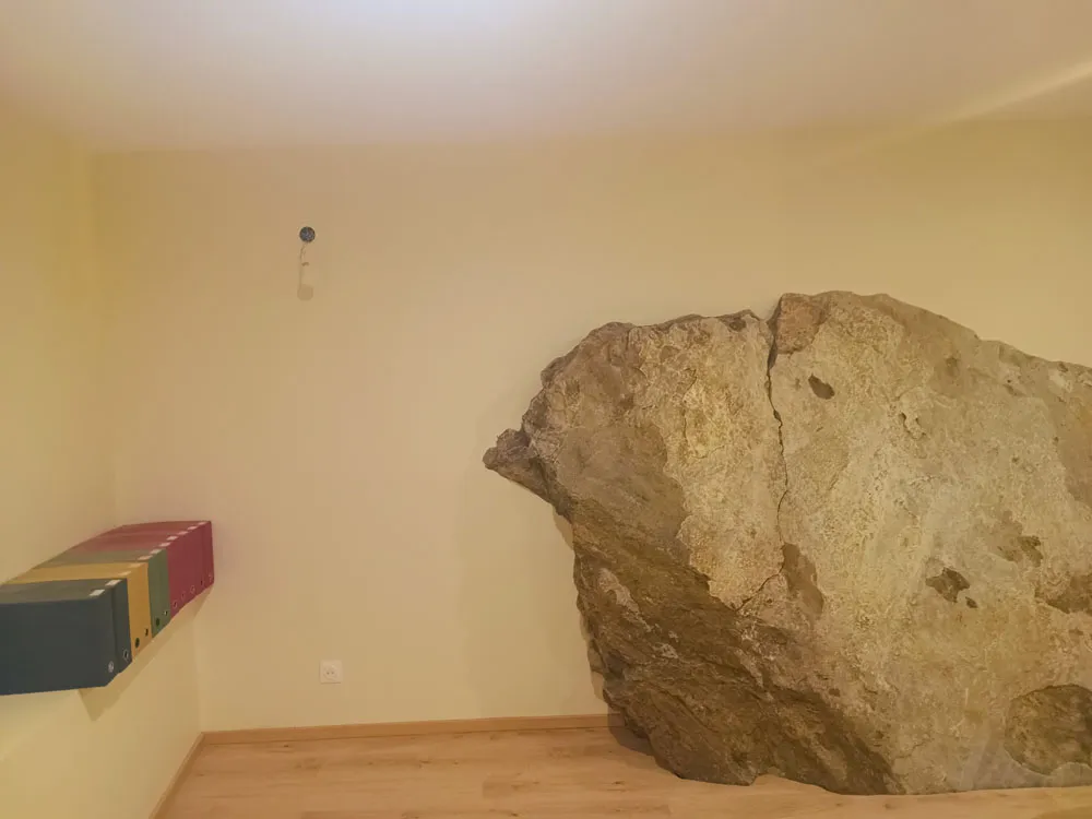 Pièce rénovée en plâtrerie sèche autour d’un rocher apparent.
