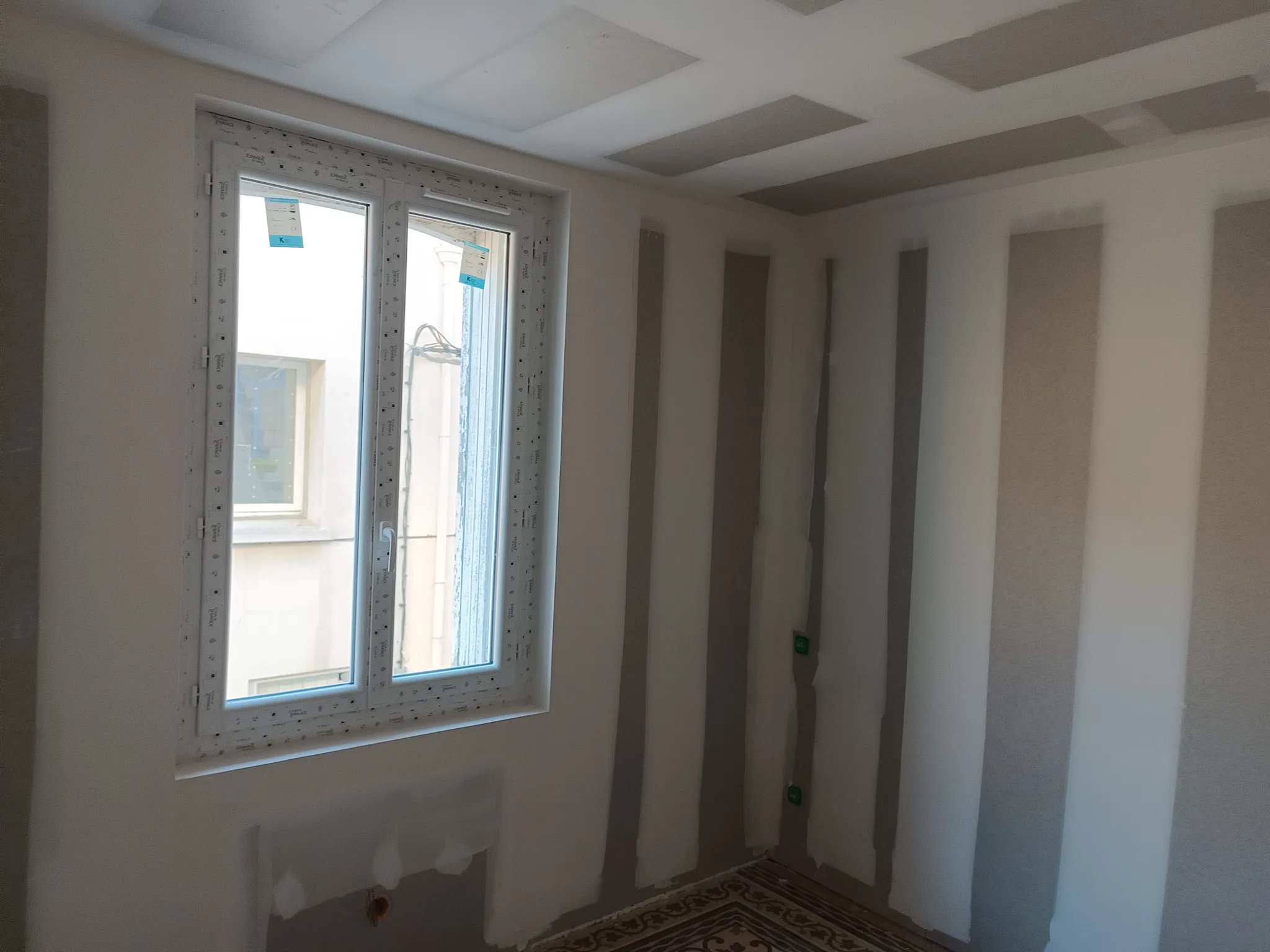 Angle de pièce avec fenêtre neuve et murs aux bandes de joints en cours