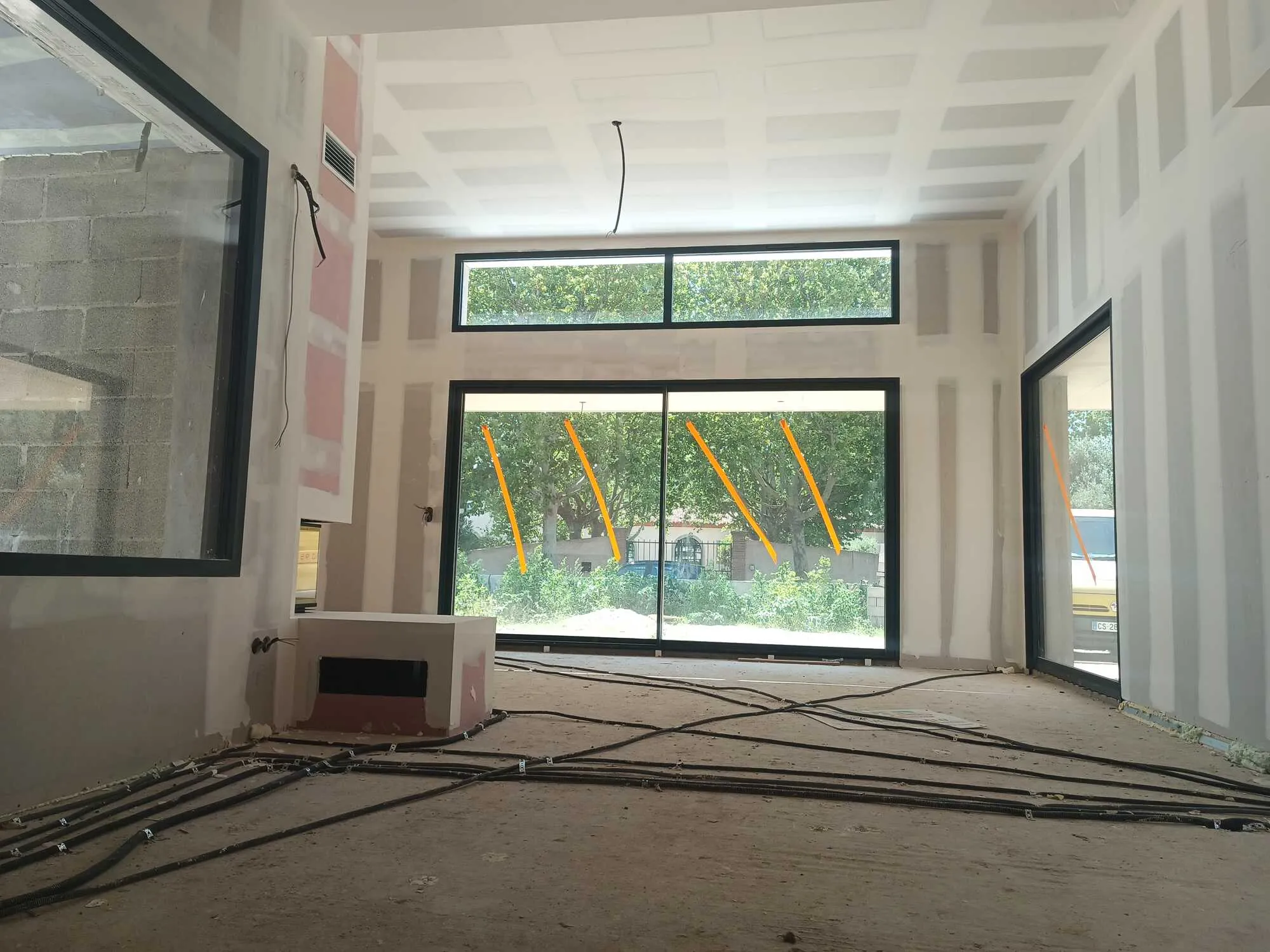 Pièce en rénovation après travaux de plâtrerie sèche et pose de placo, avec joints visibles et gaines électriques au sol.